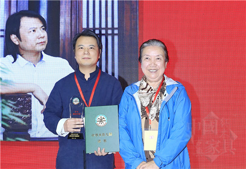 01中華兒童藝術(shù)促進(jìn)會(huì)會(huì)長(zhǎng)范崇嬿（右）為石華久（左）頒授&ldquo;中華木作大師&rdquo;榮譽(yù)